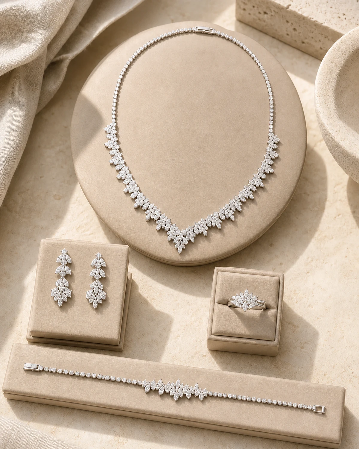 Candor catalogue hero with the complete silver-tone leaf-and-cluster necklace, matching earrings, cluster ring and fine bracelet on a warm taupe display.