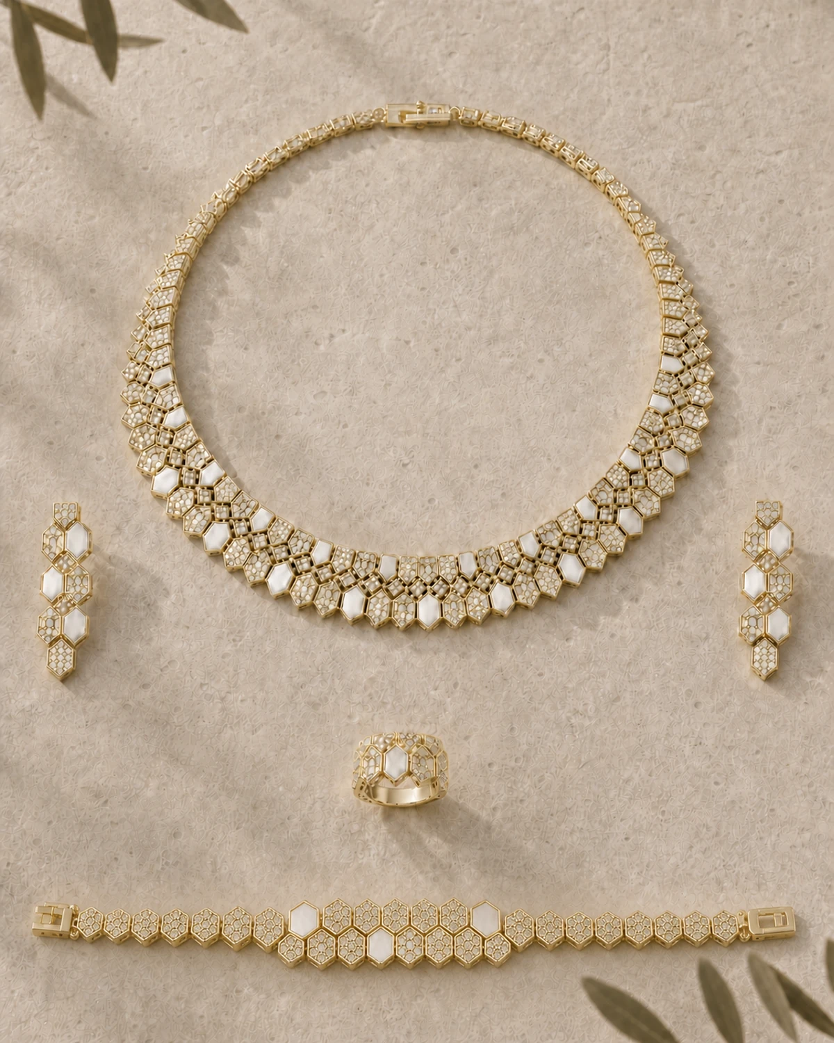 Complete five-piece Lucilla set arranged on warm taupe stone, with the layered polygon collar centred above the matching components.