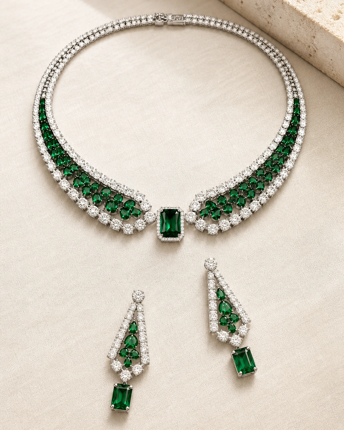 Catalogue hero of the complete Valeria set with one deep-green and clear collar necklace and two matching drop earrings on warm ivory linen and pale stone.