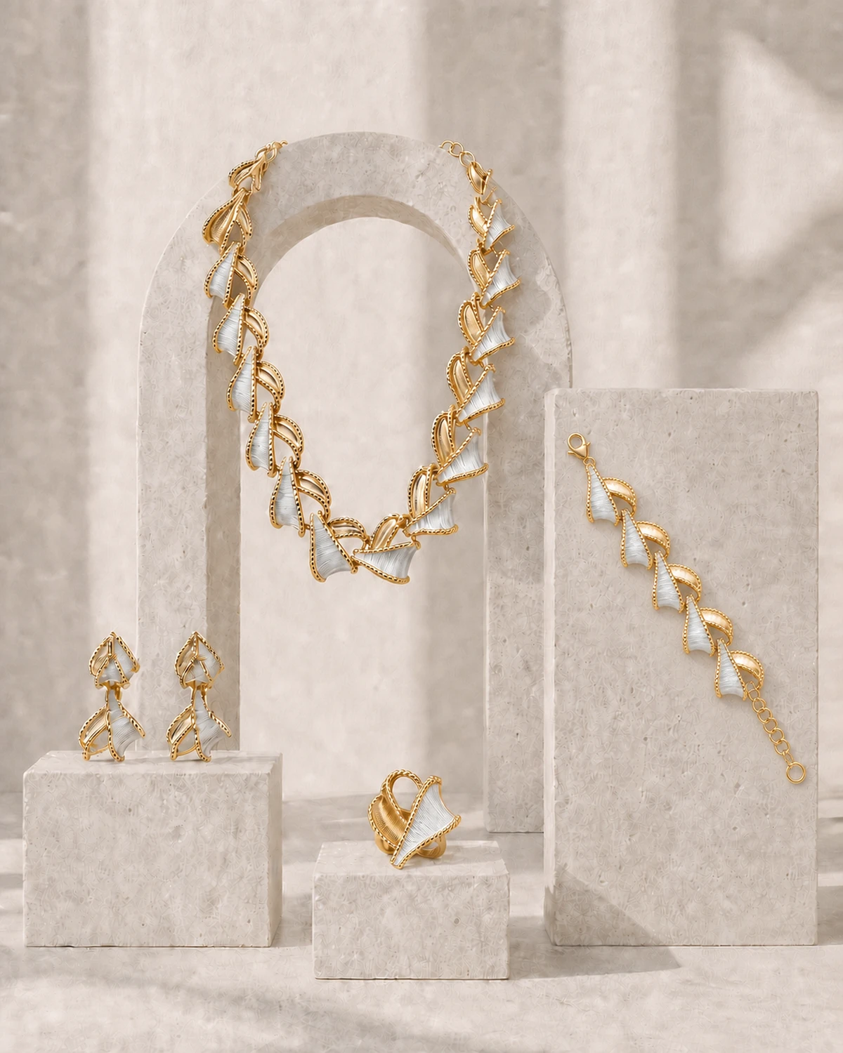 Architectural Pale Stone composition of the complete Vesper set with the necklace on an arch and the earrings, ring and short bracelet on separate blocks.