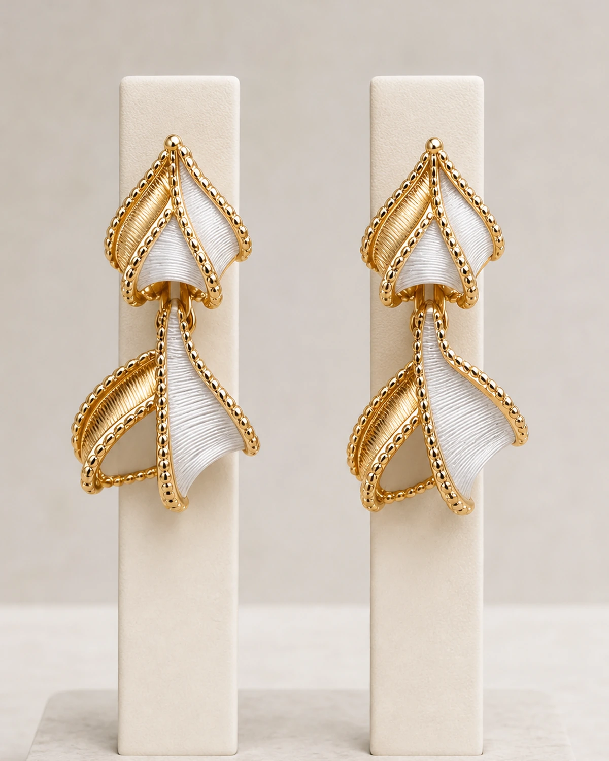 Close product view of two matching complete Vesper earrings, each built from two stacked folded fan-and-leaf motifs.
