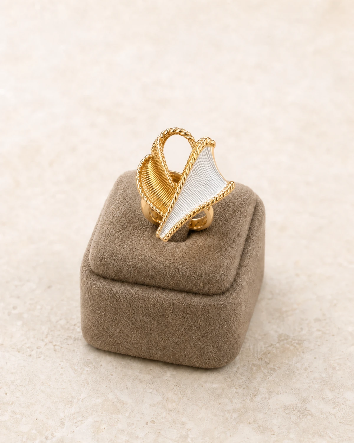 Macro product view of the compact Vesper ring with crossed pale satin-fan and warm-tone ribbed leaf forms.