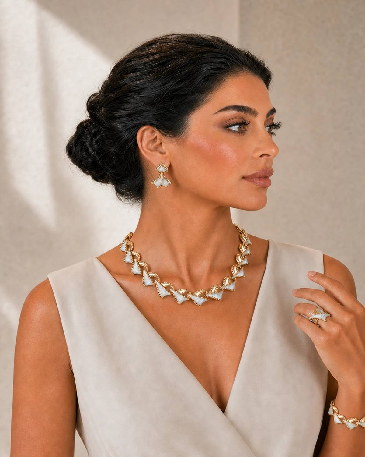 Turned portrait of Luna presenting the Vesper crossed ring and repeating bracelet with one hand while the complete necklace and nearest earring remain visible.